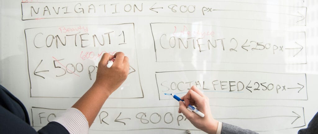 Two association members brainstorming engagement strategies on a white board with markers. 