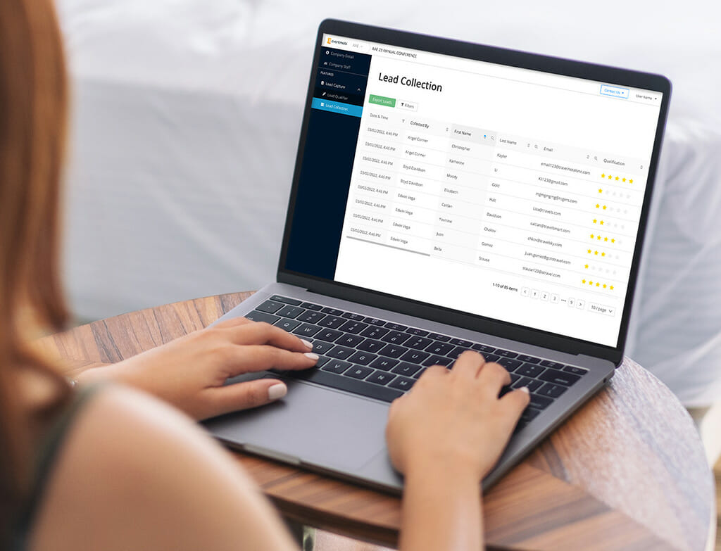 A woman at a wooden table looks at the Lead Collection portal, part of EventMobi's lead capture service.