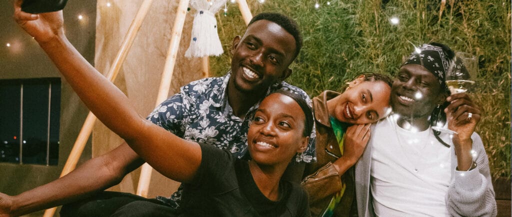 Group of happy event attendees having a picnic while they toast and take a selfie.