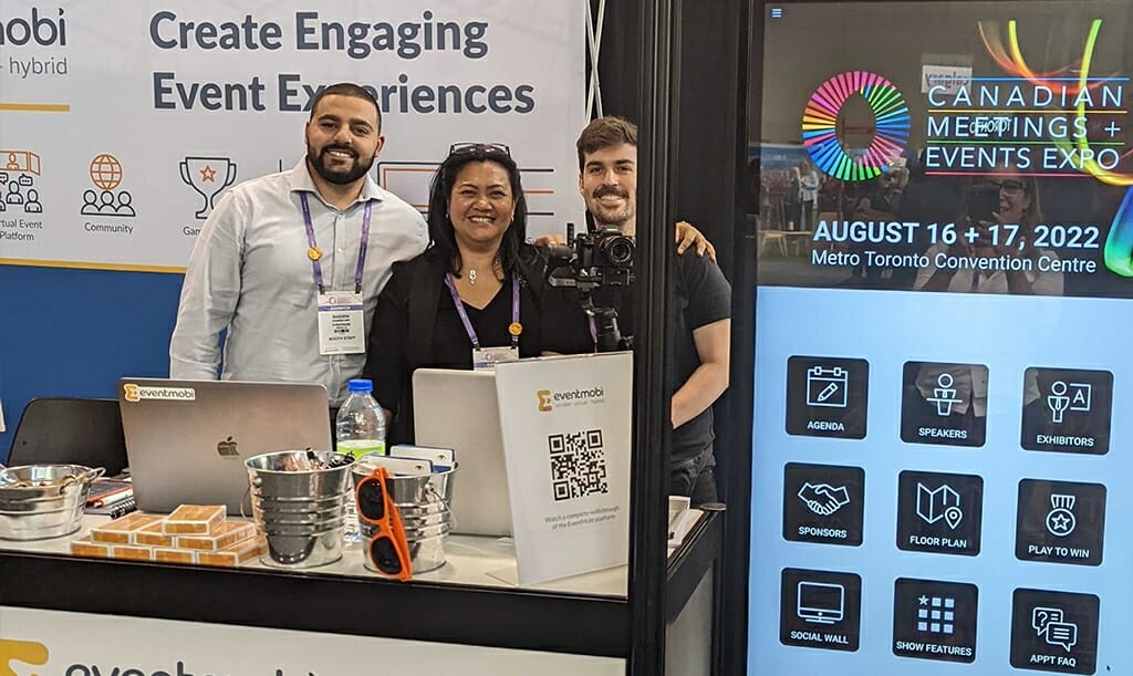 Image: 3 People Standing in front of Tradeshow Booth