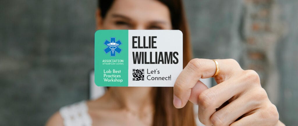 Woman holding a workshop badge in front of her, with her name standing out from the badge design.